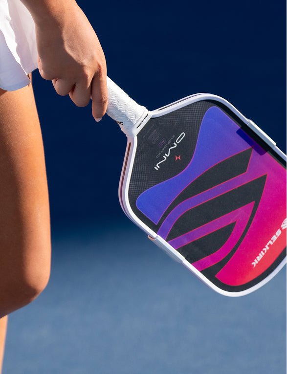 Close-up shot of an athlete holding a Apollo Axis pickleball paddle featuring a vibrant pink, purple, and blue gradient face design